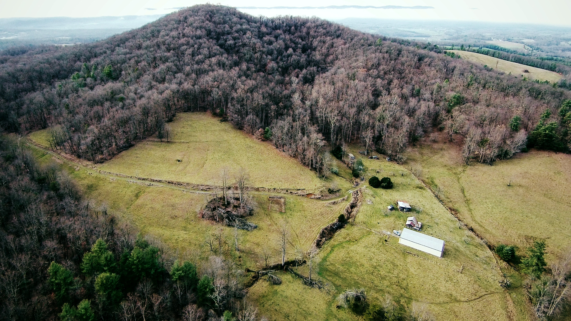 Aerial depiction of remote buildings in a small clearing surrounded by forest.